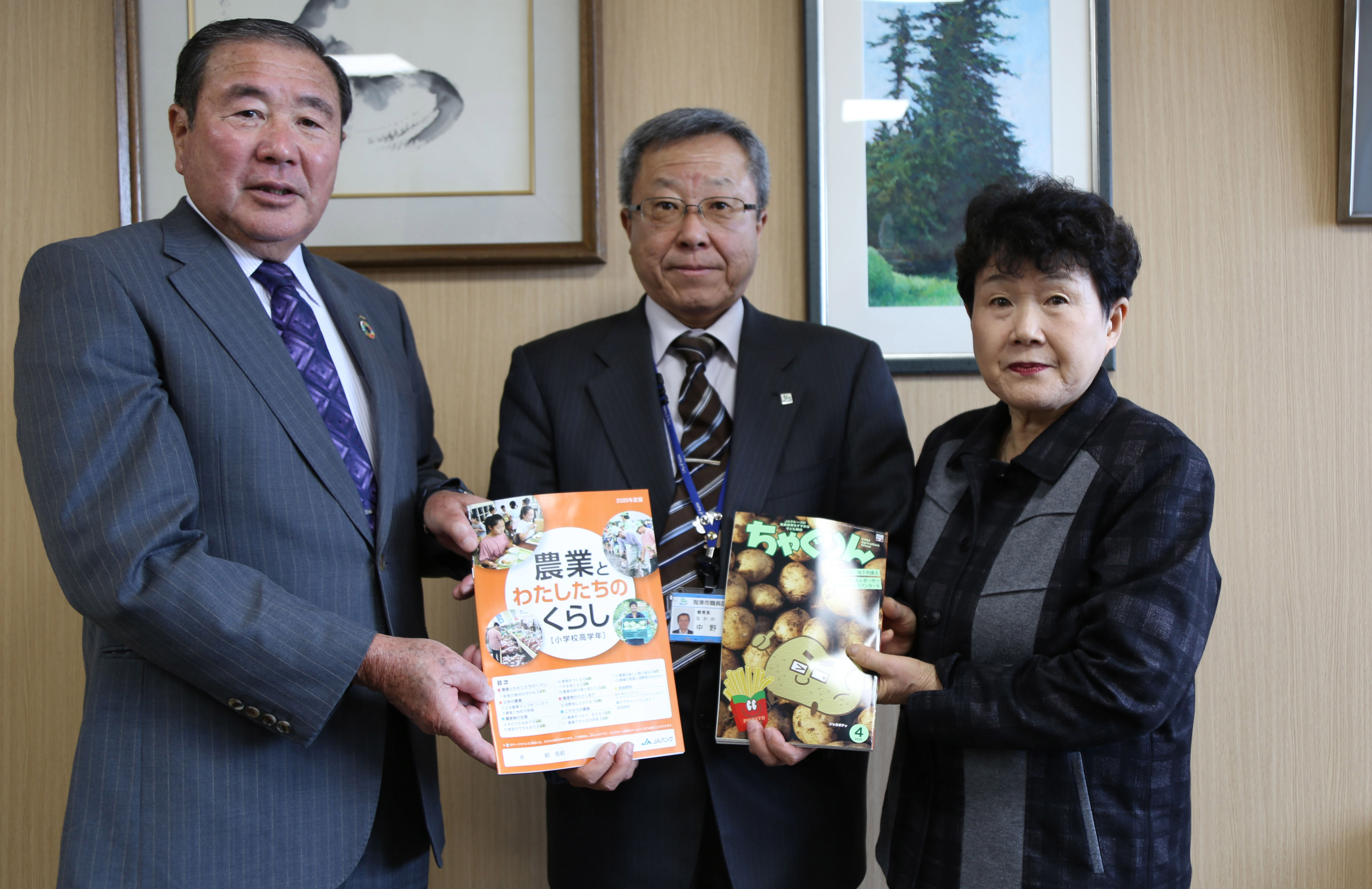 小林組合長と佐藤部長から食農教材本を受け取る中野教育長
